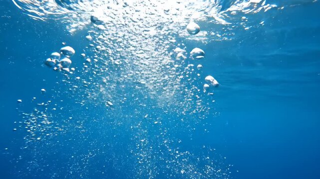 Video of underwater bubble cluster rising through clear blue water, transparent sphere texture, aquatic motion backdrop, purity and freshness theme for branding visuals.