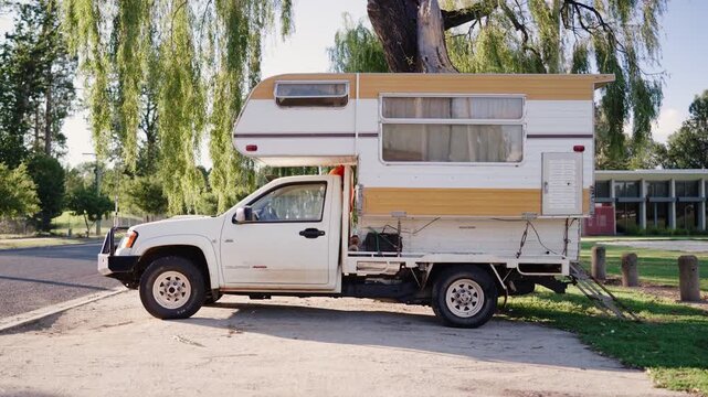 Retro vintage campervan caravan at lush road side stop beneath stunning tree