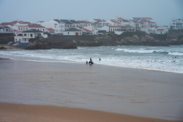 Surfers on Baleal beach, in Portugal, on a very foggy day