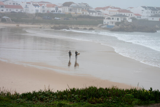 Surfers on Baleal beach, in Portugal, on a very foggy day
