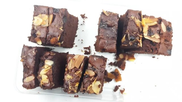 Rich chocolate almond brownies are cut into small squares displayed on a clear surface in this high angle dessert motion footage clip.