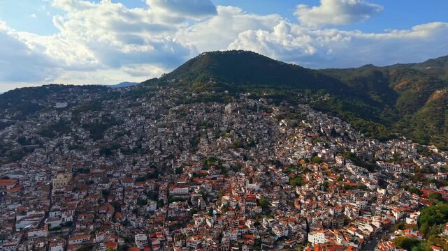 Aerial panoramic establishing shot of the magical town of Taxco in Guerrero, Mexico, with colonial architecture and Mount Atachi in the background.