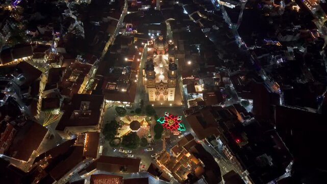 A tilt-up aerial view of the Santa Prisca temple with the Christmas flower at night in Taxco, Guerrero, Mexico
