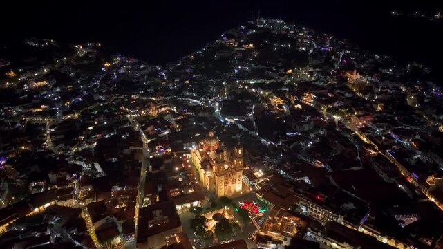 Aerial panoramic view of the city of Taxco de Alarcon, Guerrero, Mexico at night with its illuminated streets, Santa Prisca church with viceroyalty architecture.