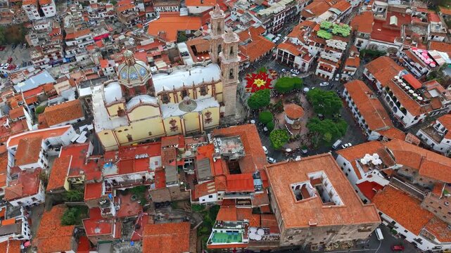 Aerial orbit over the Temple of Santa Prisca and the poinsettia flower in the city of Taxco de Alarcon, Guerrero, Mexico. High frame rate.