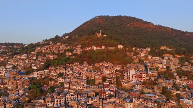 Aerial view dolly in of the Casahuates neighborhood on the slopes of Atache Hill with the monument to Christ the King in Taxco, Guerrero State, Mexico