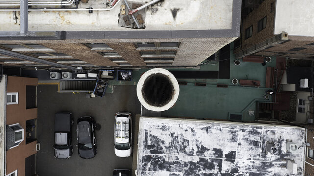Aerial view of the architectural geometry where brick facades meet green rooftops and parked cars cluster near a circular opening, Summit, New Jersey, United States.