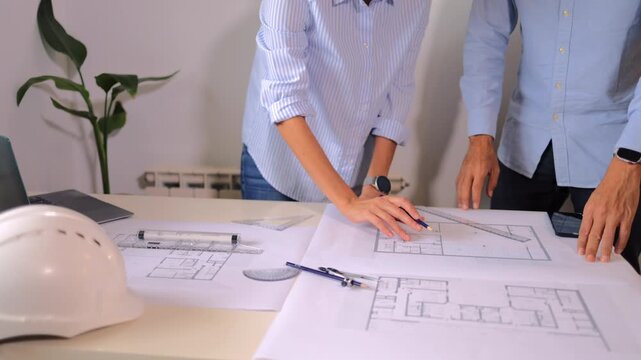 Professional architect team reviewing construction blueprints and drawing new building project plans on a drafting table while working together in a modern design office