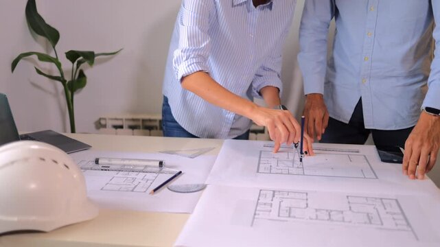 Architects discussing a building project and working together on blueprints with a compass, collaborative team brainstorming innovative designs in an architecture office