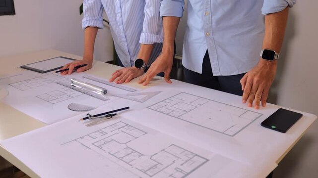 Professional architect and engineer collaborating on a building project, meticulously reviewing blueprints and technical drawings for a new apartment complex construction