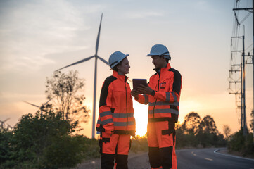 Japanese wind turbine engineer man and  female engineer working and inspecting in outdoor rural infrastructure windmill plant