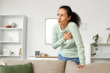 Mature woman having heart attack behind sofa at home