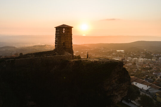 Aerial view of the ancient fortress silhouetted against the warm glow of the setting sun, casting long shadows over the city, Kruje, Albania.