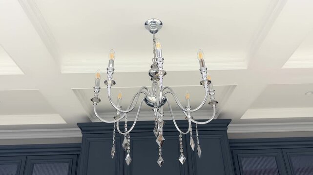Polished chrome crystal chandelier suspended from white architectural coffered ceiling design