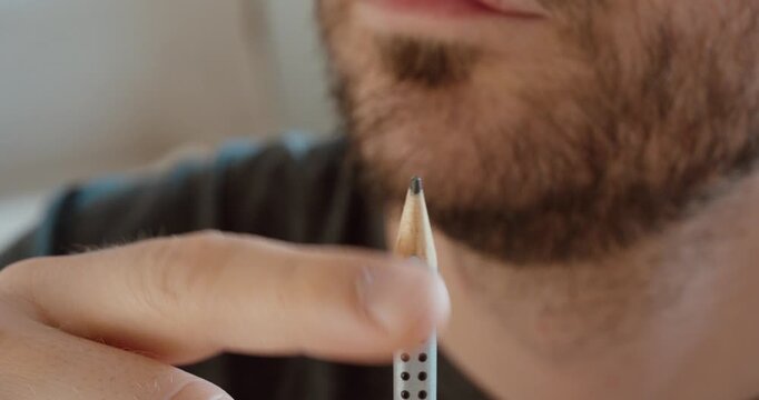 Close-up of a man holding a sharpened pencil tip.