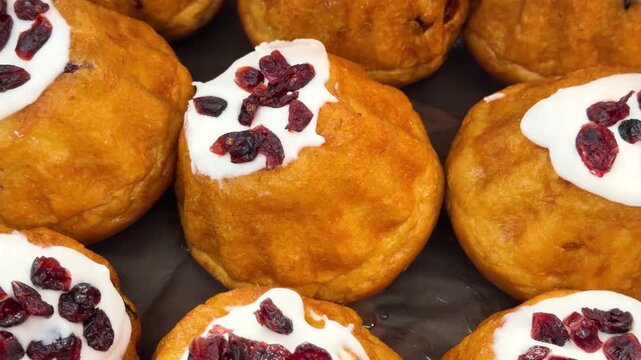 Golden small cakes topped with white icing and dried cranberries