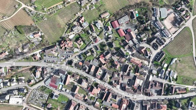 Aerial view of buildings with red roofs surrounded by lush green and brown fields, creating a patchwork quilt effect, Mittelwihr, Grand Est, France.