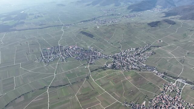 Aerial view of Mittelwihr village nestled amongst the patchwork quilt of vineyards, a verdant tapestry under the vast sky, Mittelwihr, Grand Est, France.