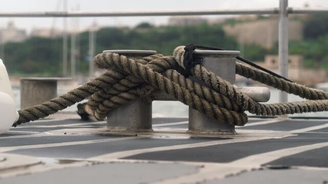 Ship mooring bitts on a swaying deck with a defocused city view in the background