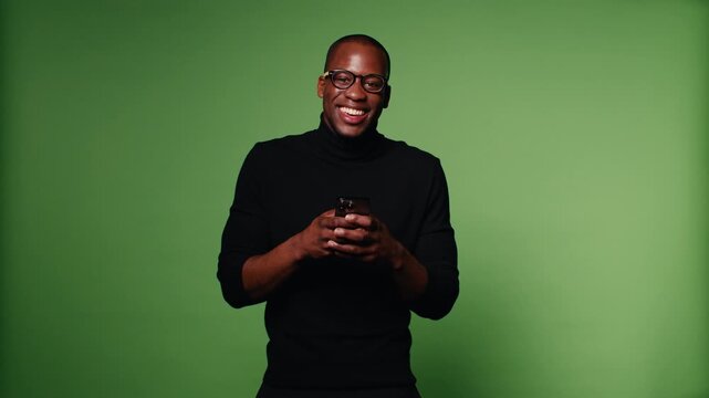 Happy black man using his smartphone on green background