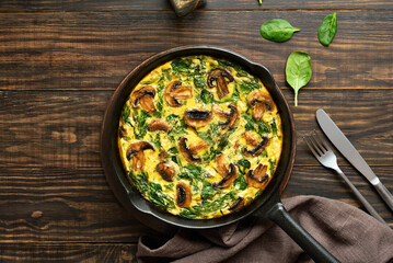 Fototapeta premium Frittata with spinach and champignon mushrooms in cast iron skillet