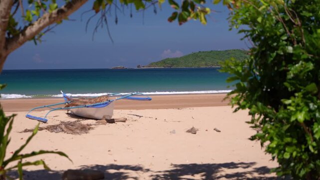 Traditional Filipino bangka boat resting on sandy tropical beach at Dagmay Beach in El Nido Palawan Philippines.