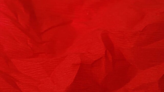 Textured red fabric background showing numerous intricate folds and wrinkles used as abstract design