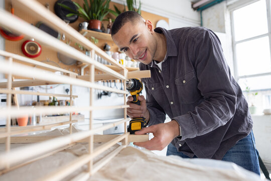 Young man using a screw driver to repair a piece of furniture 