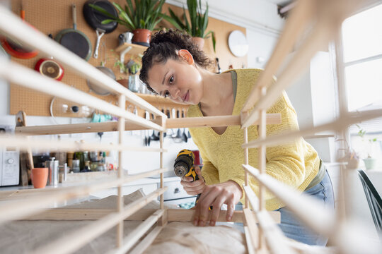Young woman using a screwdriver to repair a piece of furniture