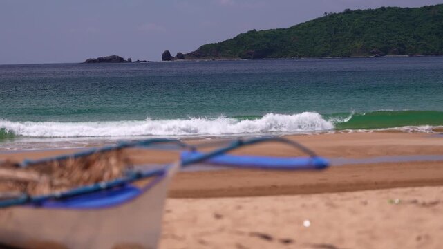 Traditional Filipino bangka boat resting on quiet sandy beach with turquoise ocean in Dagmay Beach Palawan Philippines.