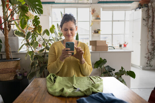 Smiling Woman taking a photo of clothing to sell online