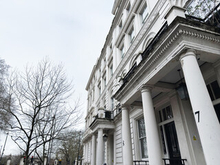 Naklejka premium Elegant white terrace house in London with columns and balconies on a cloudy day