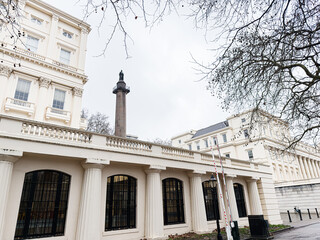 Naklejka premium Historic neoclassical Carlton House Terrace building with colonnade and statue in London, UK, an elegant urban facade scene