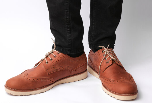 Male legs in skinny jeans and brown leather brogue boots on a white background. Men's style