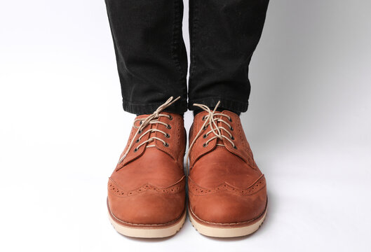 Male legs in skinny jeans and brown leather brogue boots on a white background. Men's style