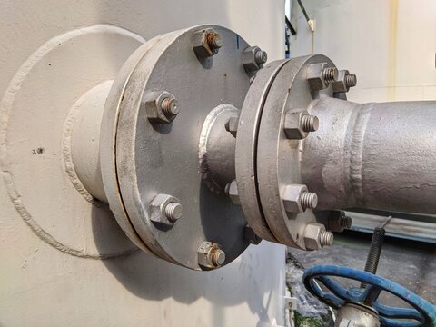 Industrial steel pipe flange connection with bolts and nuts on a pressurized storage tank in a chemical processing plant or refinery factory.