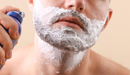 Man's face with shaving foam on a beige background