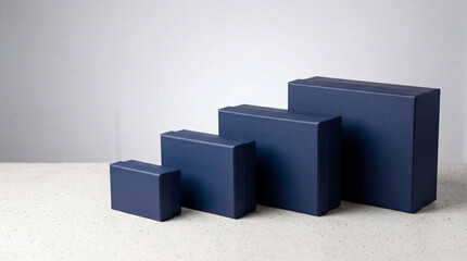 Obraz premium Dark Blue Gift Boxes Arranged by Size on White Table - Product Packaging