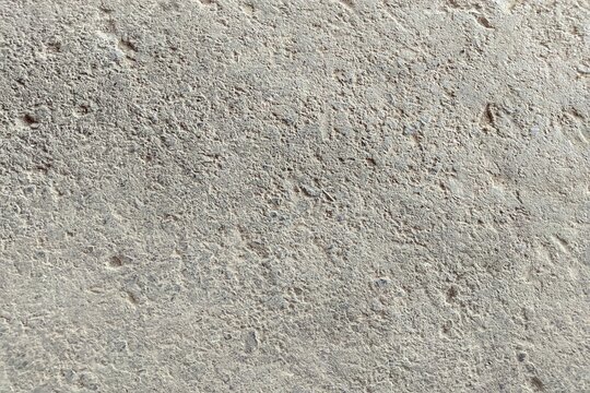 Rough sandy concrete texture background. Natural beige stone surface with grainy soil particles and weathered grit. High-resolution outdoor ground texture for architectural design and overlays.