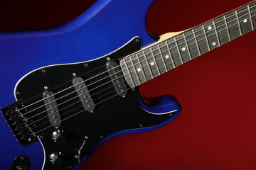Modern electric guitar on red background, closeup