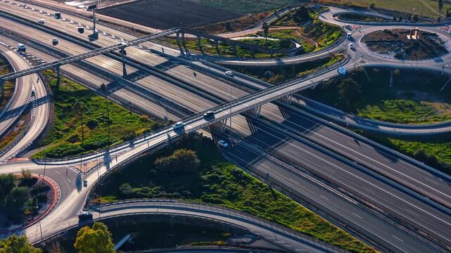 Aerial perspective of complex highway junction and roundabouts. Low angle sunlight over multi-level road intersection with ramps, bridges and long shadows.