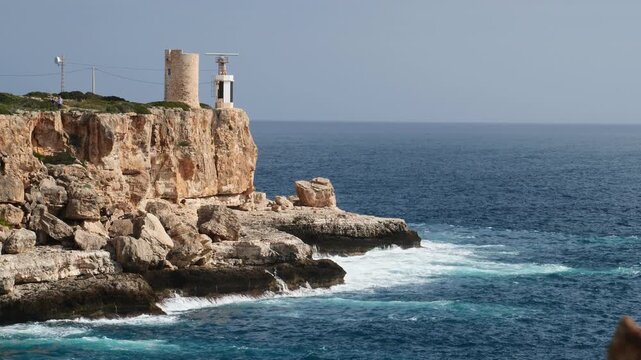 Slow motion of waves crashing on the rocks under the Torre d'en Beu lighthouse. Cala Figuera, Mallorca, Spain.