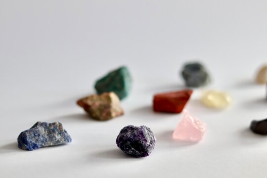 Collection of various raw colorful gemstones and minerals on a white background.