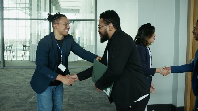 Diverse business professionals greet each other with handshakes at a corporate event