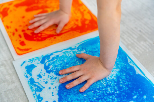 Child hands pressing colorful sensory gel mats creating moving patterns during tactile play. Sensory stimulation and occupational therapy concept for autism support and sensory integration development