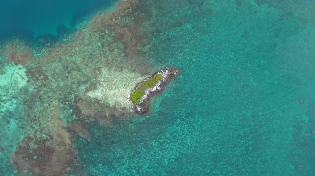 Aerial view of Camar Rock Island, a rocky islet with green vegetation amidst the turquoise waters, creating a captivating contrast, Jepara Regency, Indonesia.