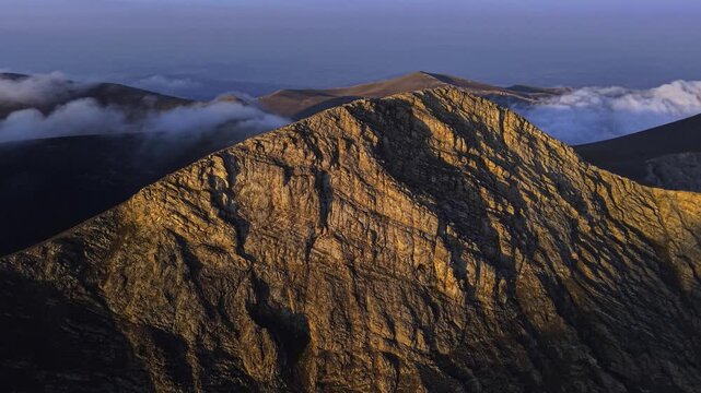 Aerial view of rugged mountain peaks piercing through scattered clouds, showcasing nature's grandeur and serene beauty, Mount Olympus, Larissa, Greece.