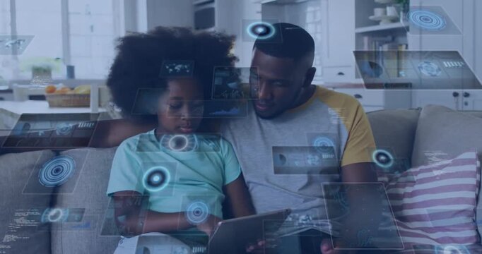 Animation of data over happy african american father and daughter using tablet relaxing at home