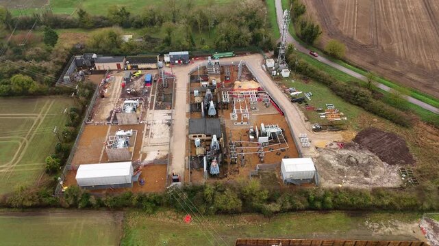 Aerial view of an electrical substation surrounded by solar panels and battery energy storage systems, contrasting against the brown fields, Burwell, United Kingdom.