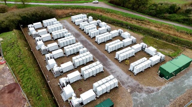 Aerial view of rows of battery energy storage systems contrasting with the green grass, creating an industrial landscape, Burwell, United Kingdom.